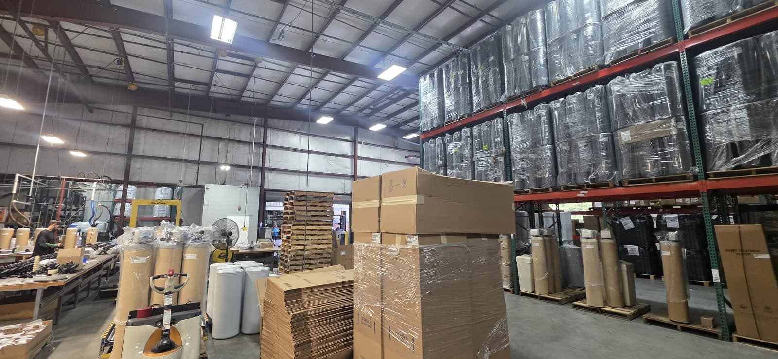 Assembly and packing floor with brine tanks, wrapped systems on racking, and boxed units